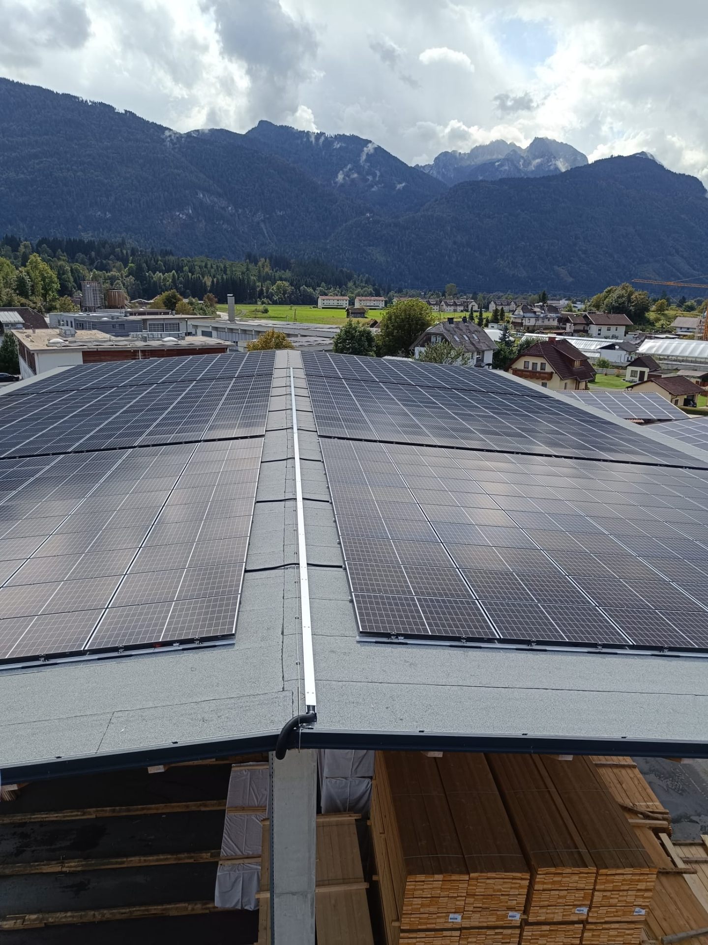 Großflächige Photovoltaik-Anlage auf einer Gewerbehalle mit Blick auf die Alpen