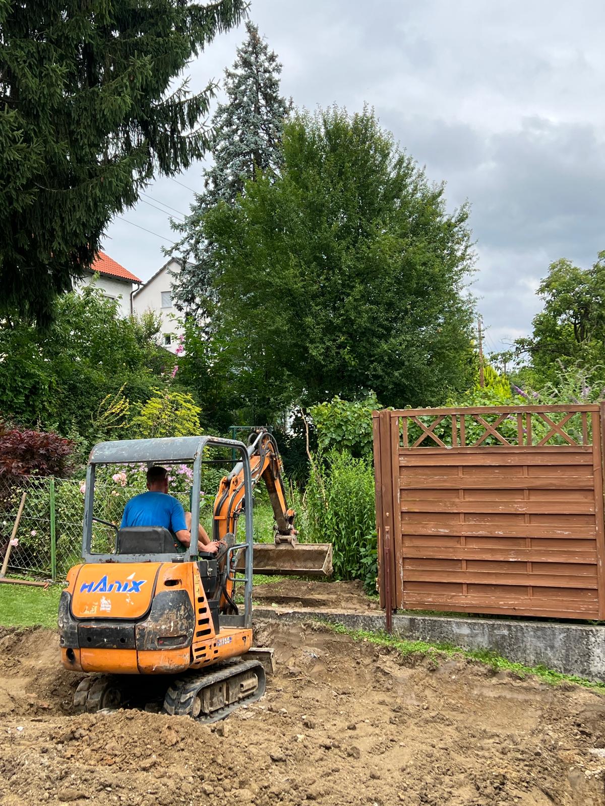 Hanix Minibagger beim Aushub für eine Gartenzufahrt neben einem Holzzaun