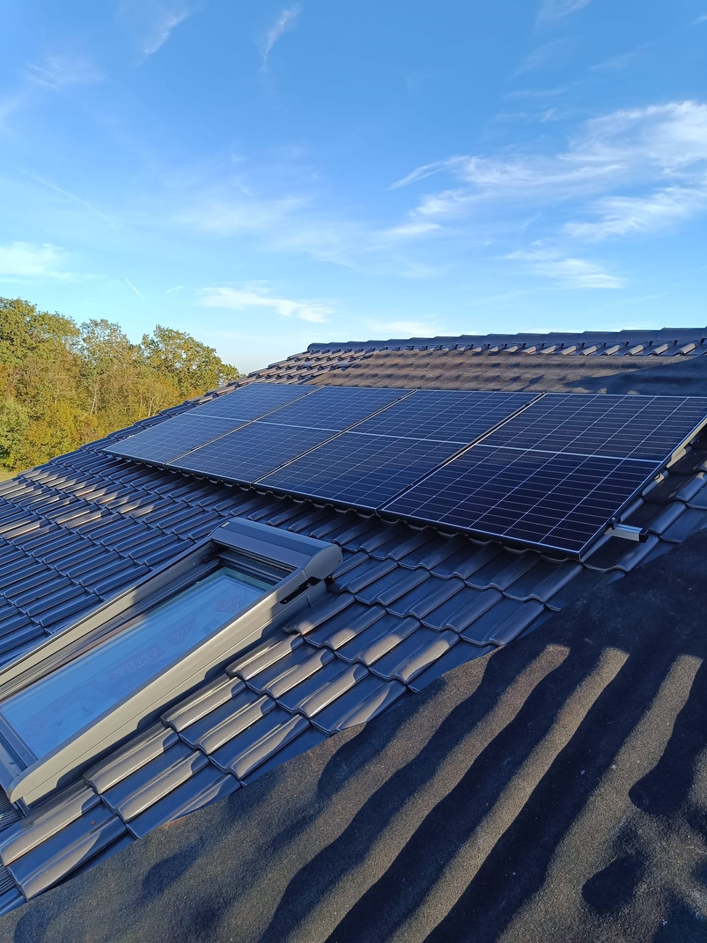 Photovoltaik-Module installiert um ein Velux-Dachfenster auf einem Wohnhaus-Ziegeldach