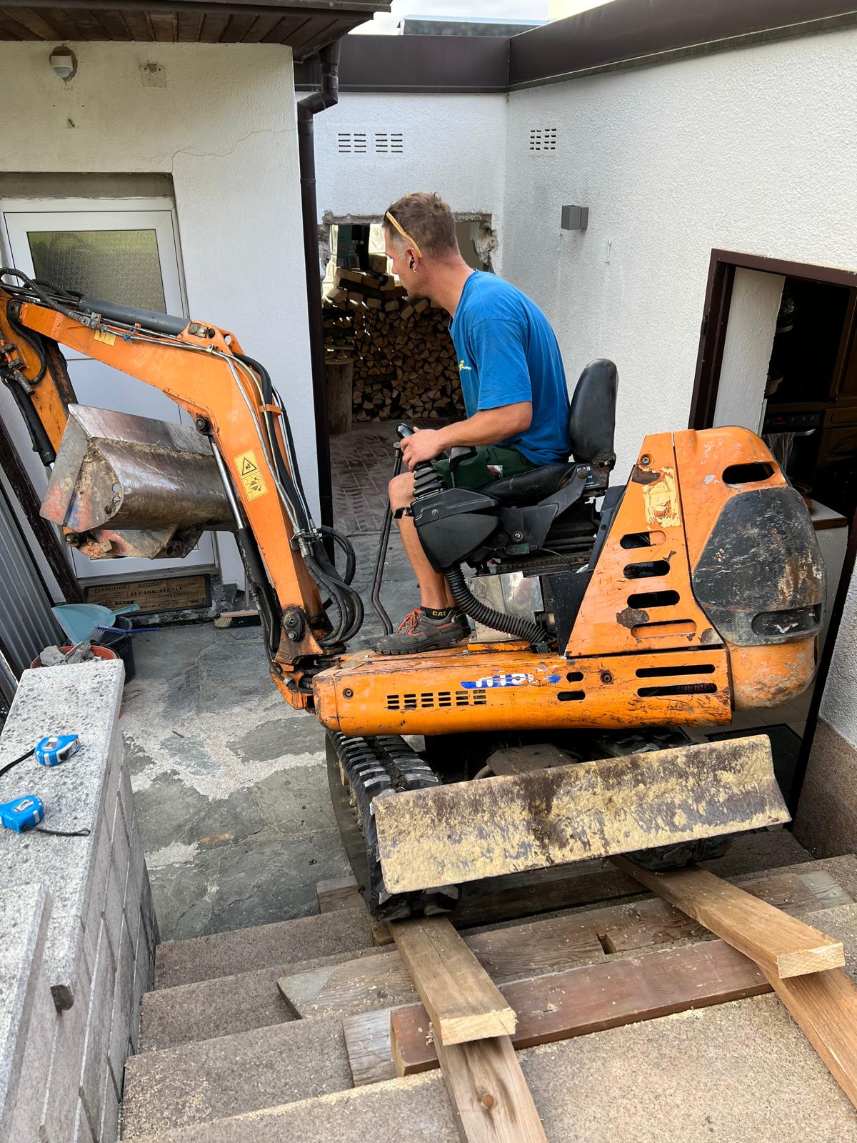 Mikrobagger im Innenbereich eines Hauses beim Stemmen einer Wandöffnung